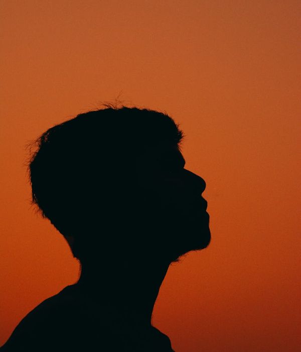 Silhouette of a person meditating against a simple background.